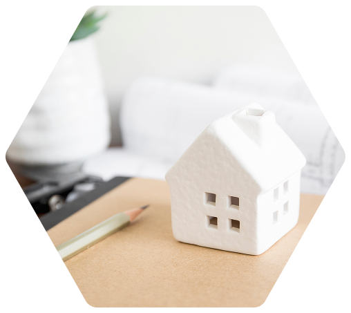 Nahaufnahme von einem weißen Miniaturhaus, das auf einem Notizblock steht