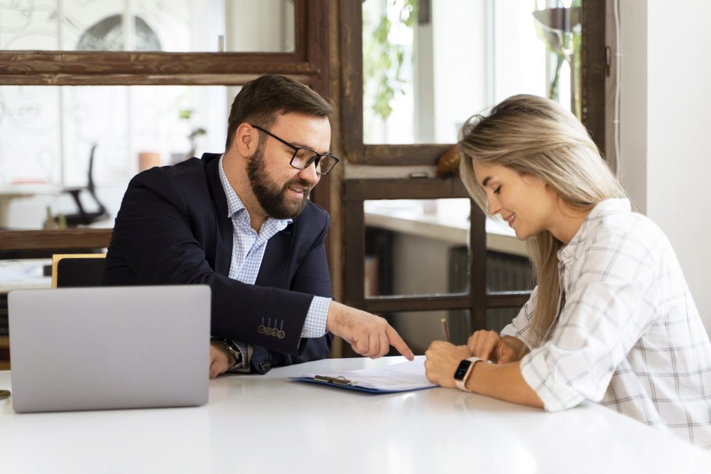 Männliche Person präsentiert einer weiblichen Person Information auf einem Blatt